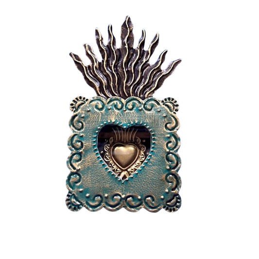 Decorative metal heart-shaped object with flame-like top on a white background