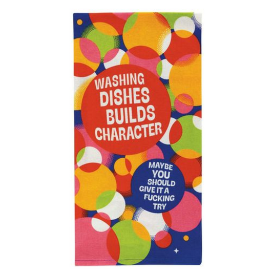 A colorful kitchen towel with text 'Washing dishes builds character' and a playful phrase 'MAYBE YOU SHOULD GIVE WASHING Dishes A TRY - IT'S NOT AS EASY AS IT LOOKS.'.