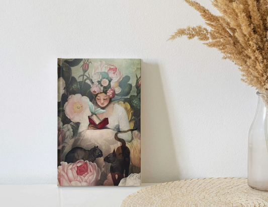 A dreamy vintage look front cover of the journal featuring a girl reading amongst florals and two black cats. 
