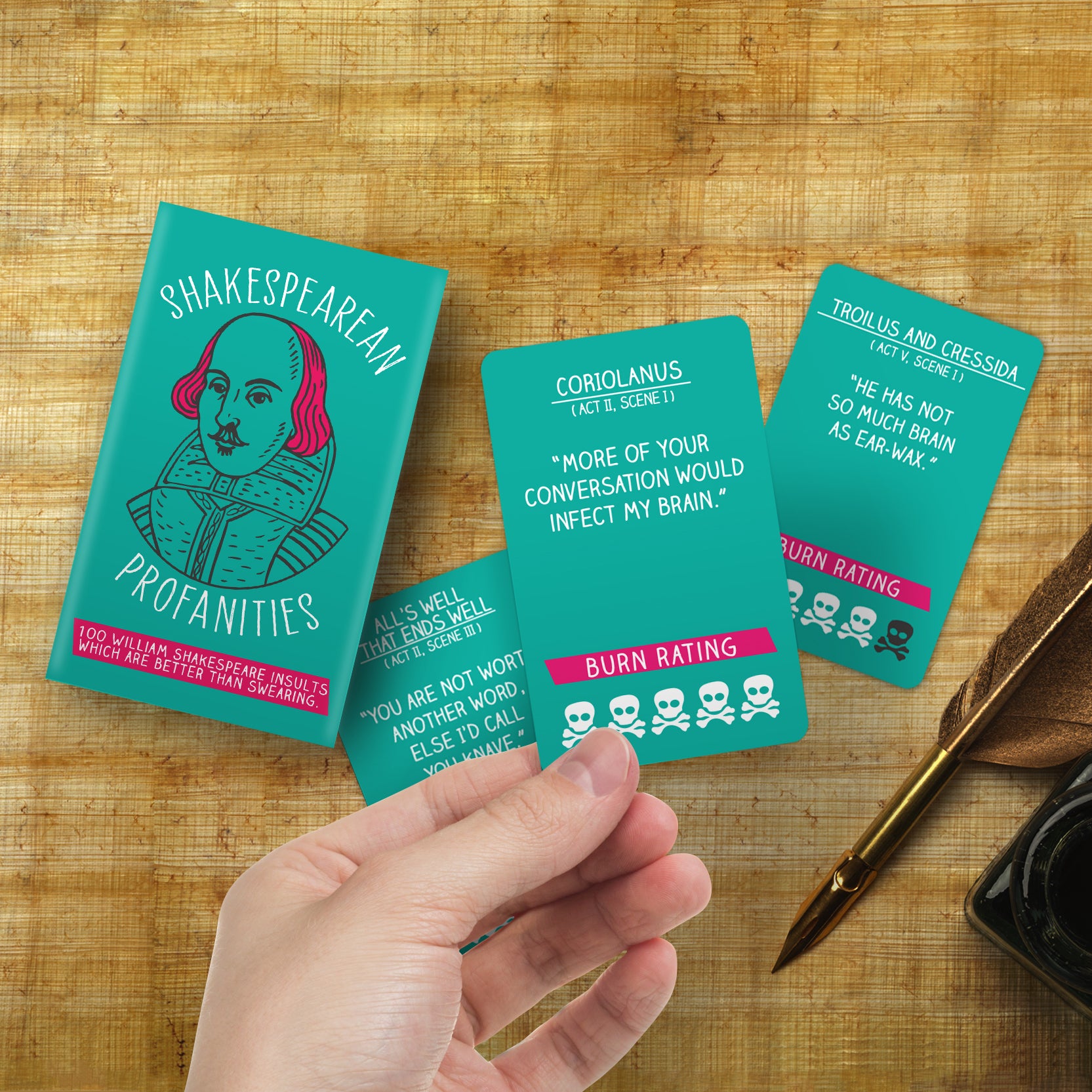 A hand showing Shakespearean Profanities cards on a brown background