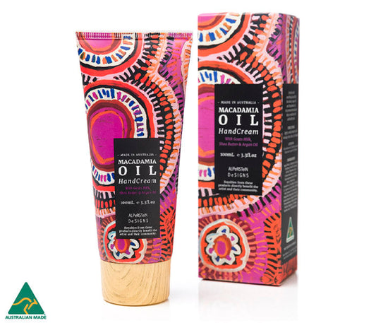 A tube and packaging of Macadamia oil & goat's milk hand cream, art by Murdie Morris on a white background.