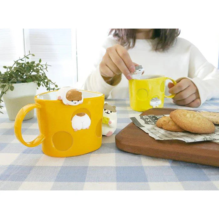 Two yellow mugs with bear-shaped handles on a checkered tablecloth, one being held by a person.