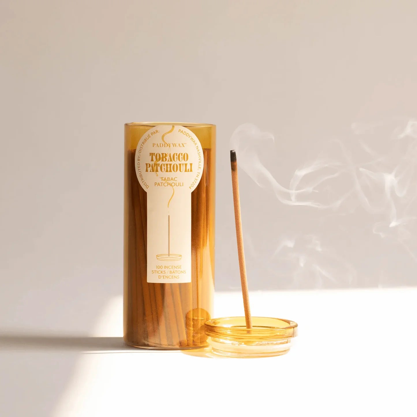 Tobacco Patchouli candle with incense stick on a light background