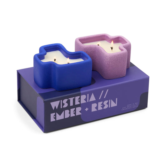 Two jigsaw shaped  candles in blue and pink holders on a purple base with text 'Wisteria // Ember + Resin'.