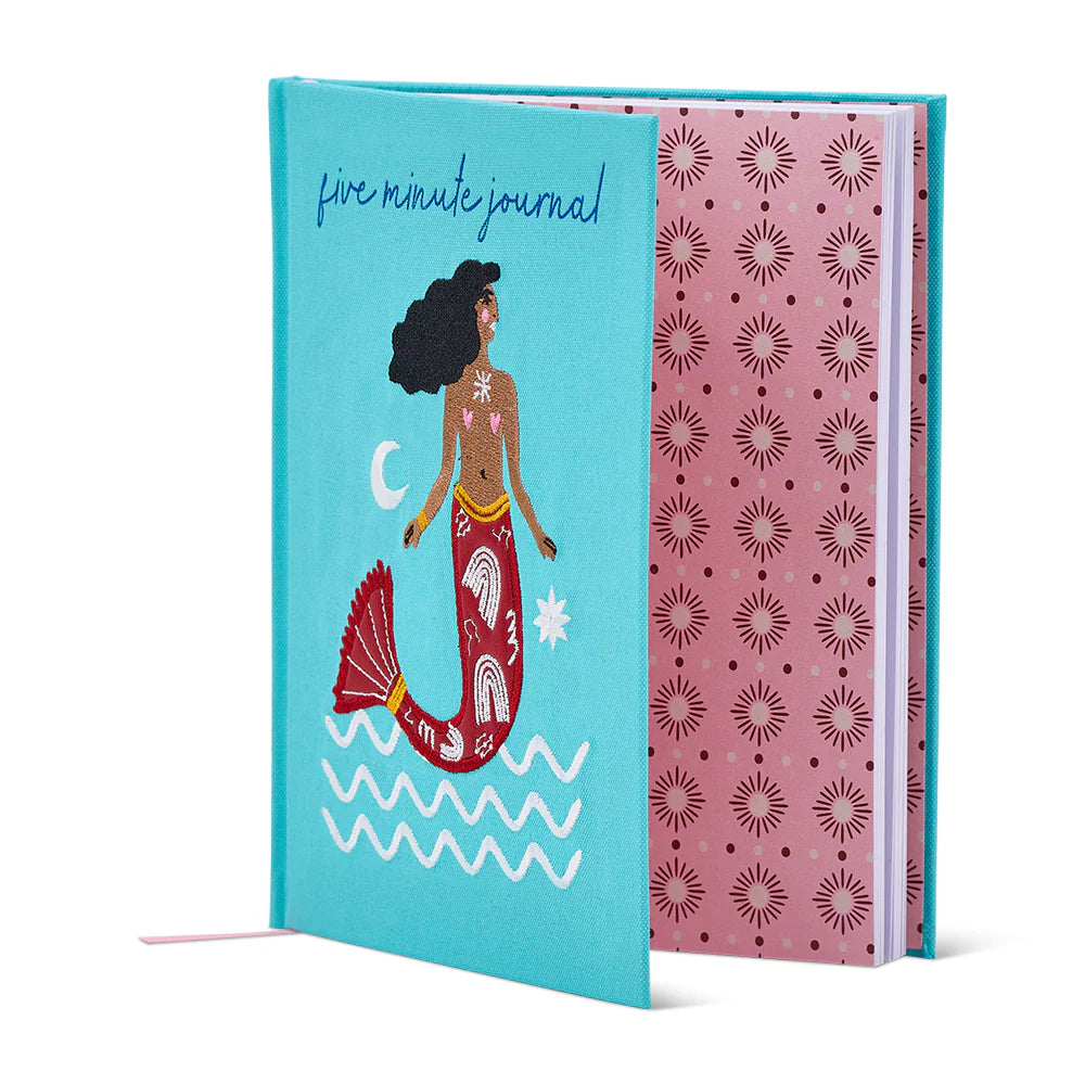 Open Journal with mermaid illustration on a blue cover and pink patterned inside leaf on a white background