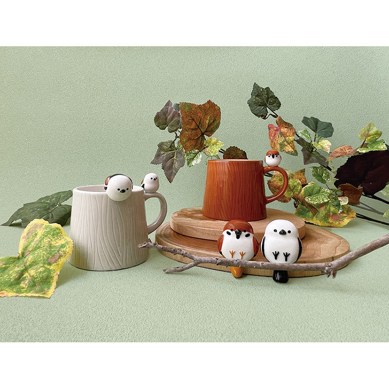 Two mugs with decorative birds on a light green background