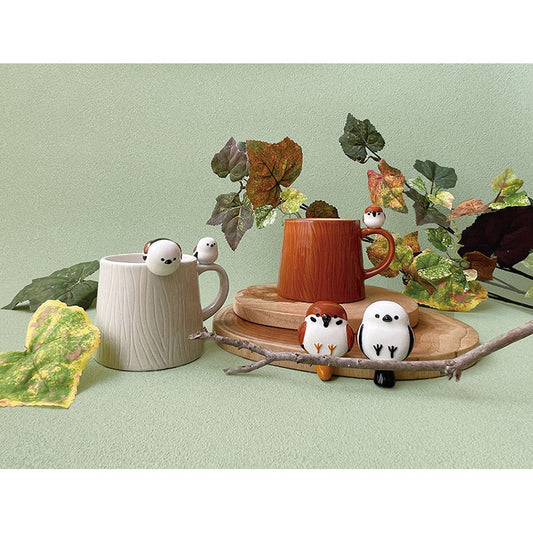 Two mugs with decorative birds on a light green background