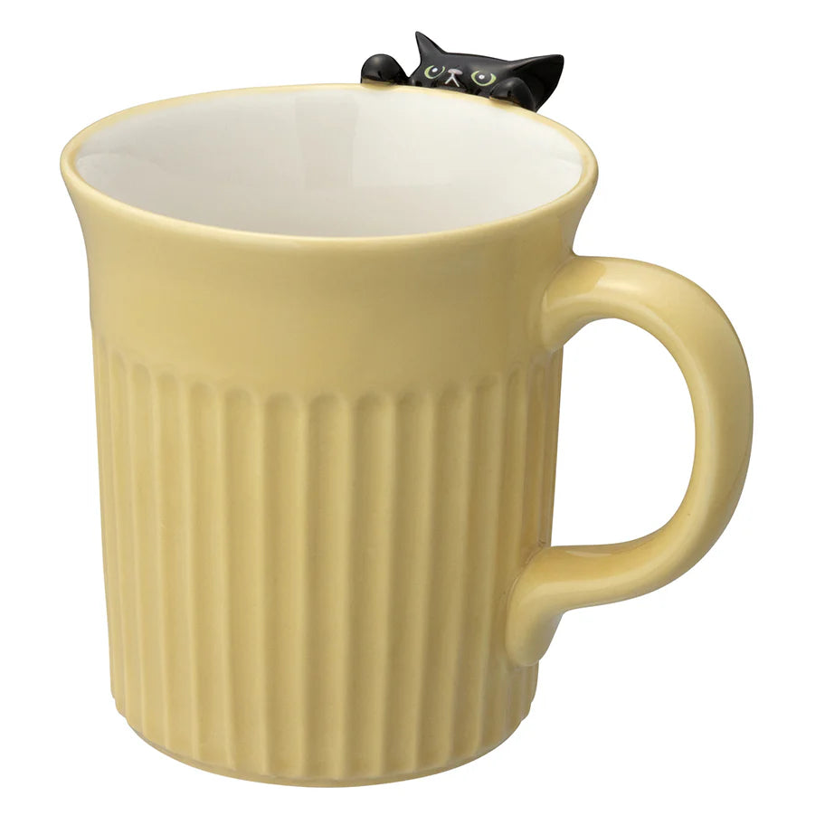Yellow mug with a black cat-shaped object on top against a white background