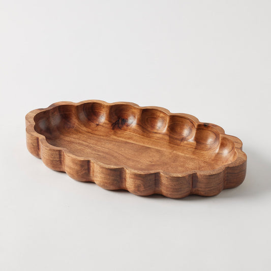 Wooden serving dish with scalloped edges on a white background
