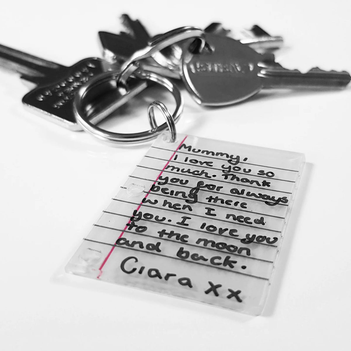 A set of keys and a small accessory in the shape of the letter with texta script on a white background.