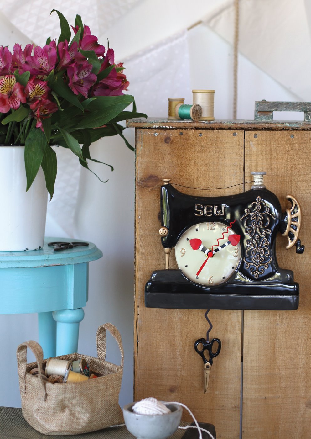 Vintage-style clock on a wooden cabinet with flowers and a basket in the background