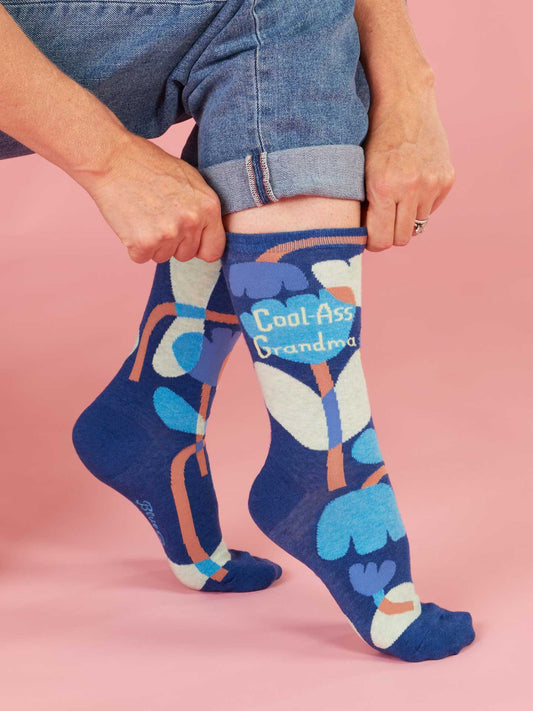 Person wearing blue socks with colorful patterns and text on a pink background