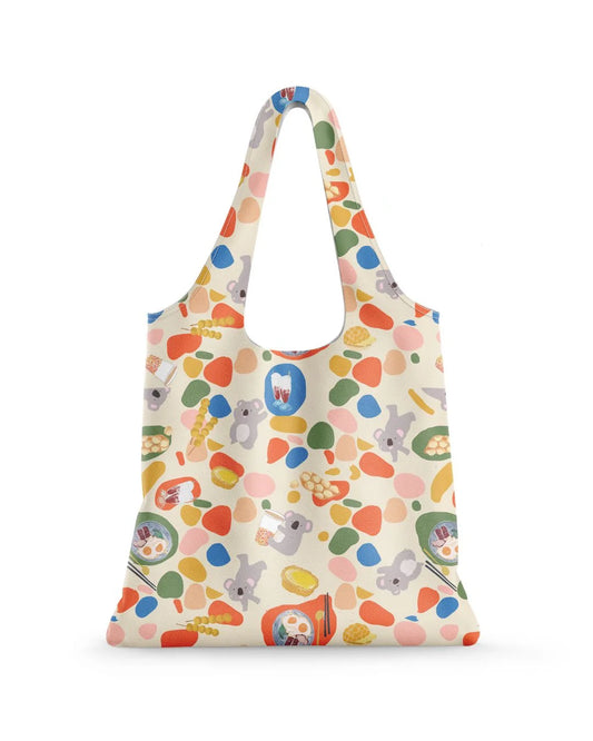 A colourful  shopping bag featuring koalas, spots and plates of food and drinks. The background is white.