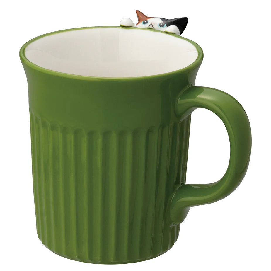 Green mug with a cat-shaped object peeking out from inside on a white background