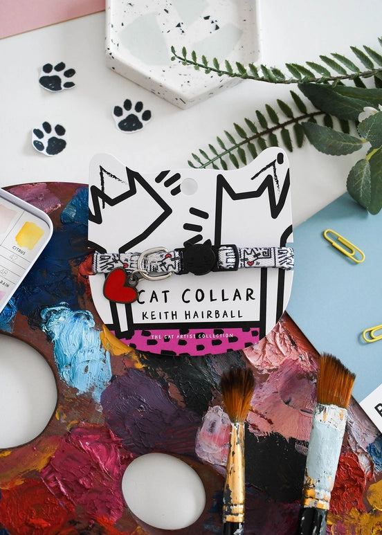Card with 'Cat Collar Keith Hairball' design on a colorful art palette with paintbrushes and leaves.