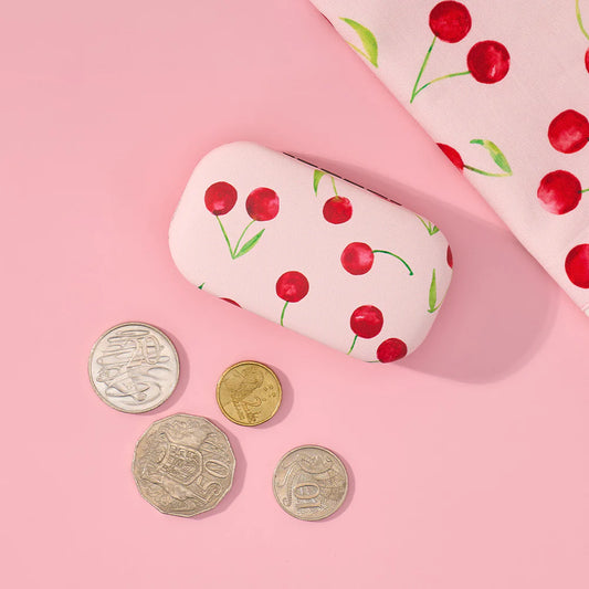 White case with red cherry design on pink background with coins