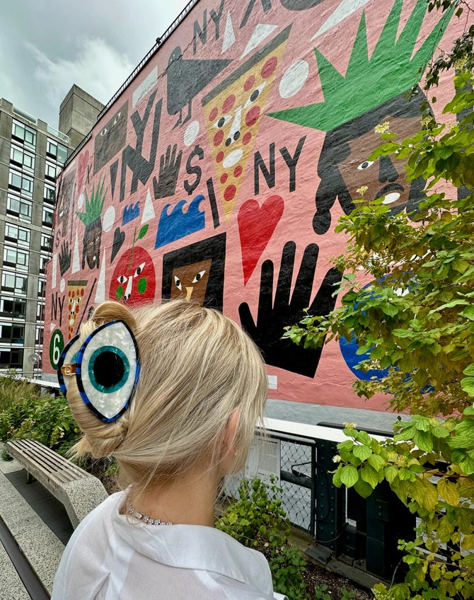 Person with colorful sunglasses looking at a large mural on a building