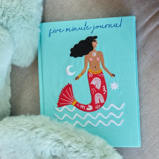Five minute journal with mermaid illustration on a textured surface