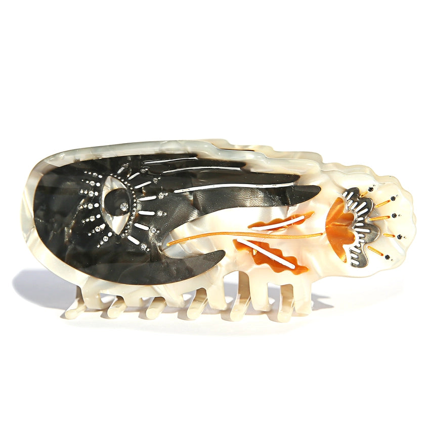 Decorative hair clip with black, white, and orange design on a white background