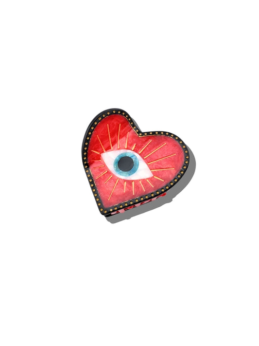 Heart-shaped red hair clip with an eye design on a white background
