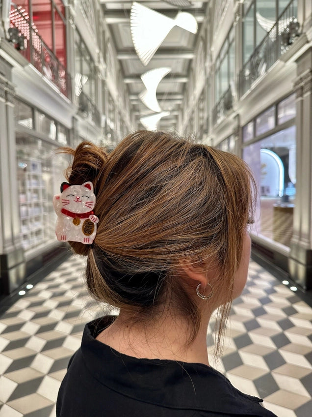 Person with a bun wearing a hair claw with a cat design in a modern building.