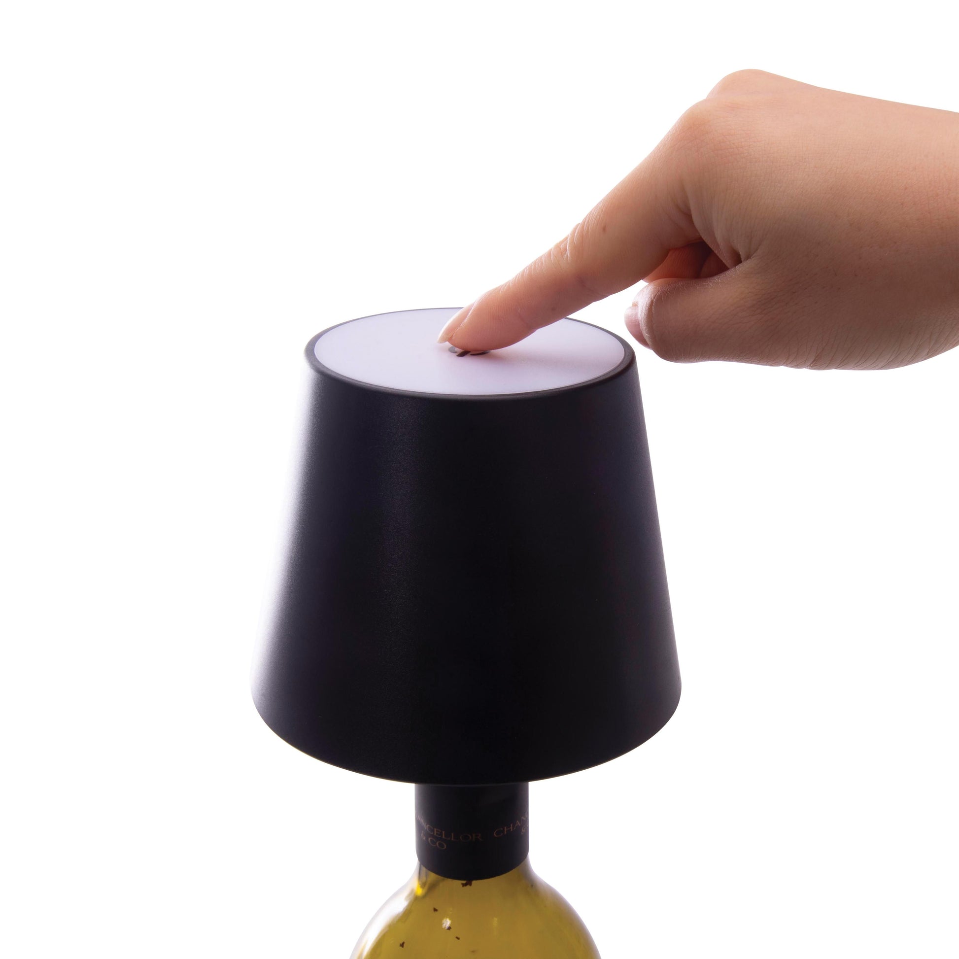 A finger pointing to a black rechargeable bottle lamp.