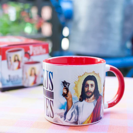 Mug with a religious design featuring a portrait of a religious figure, placed on a table with a blurred background.