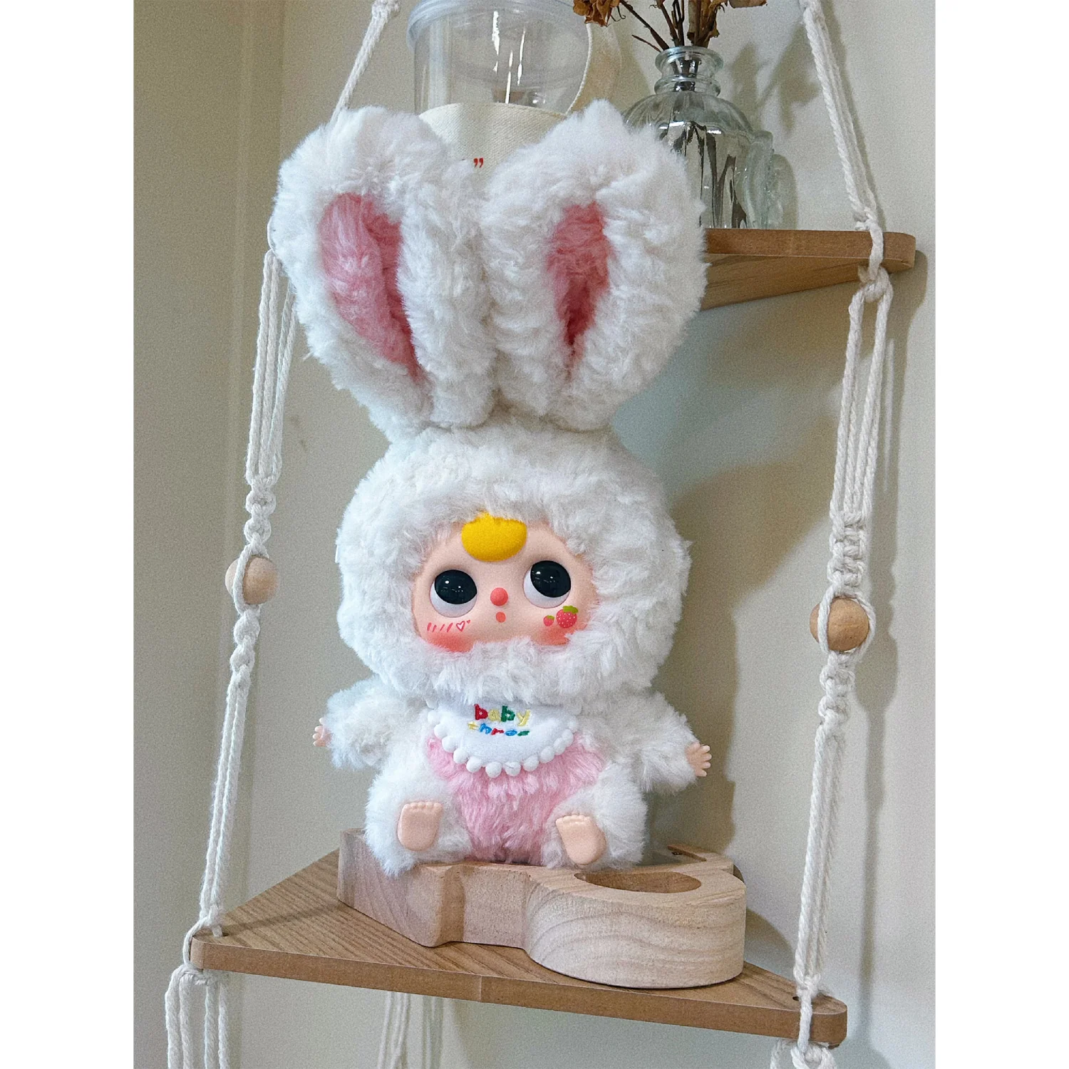White plush toy with pink accents on a wooden shelf