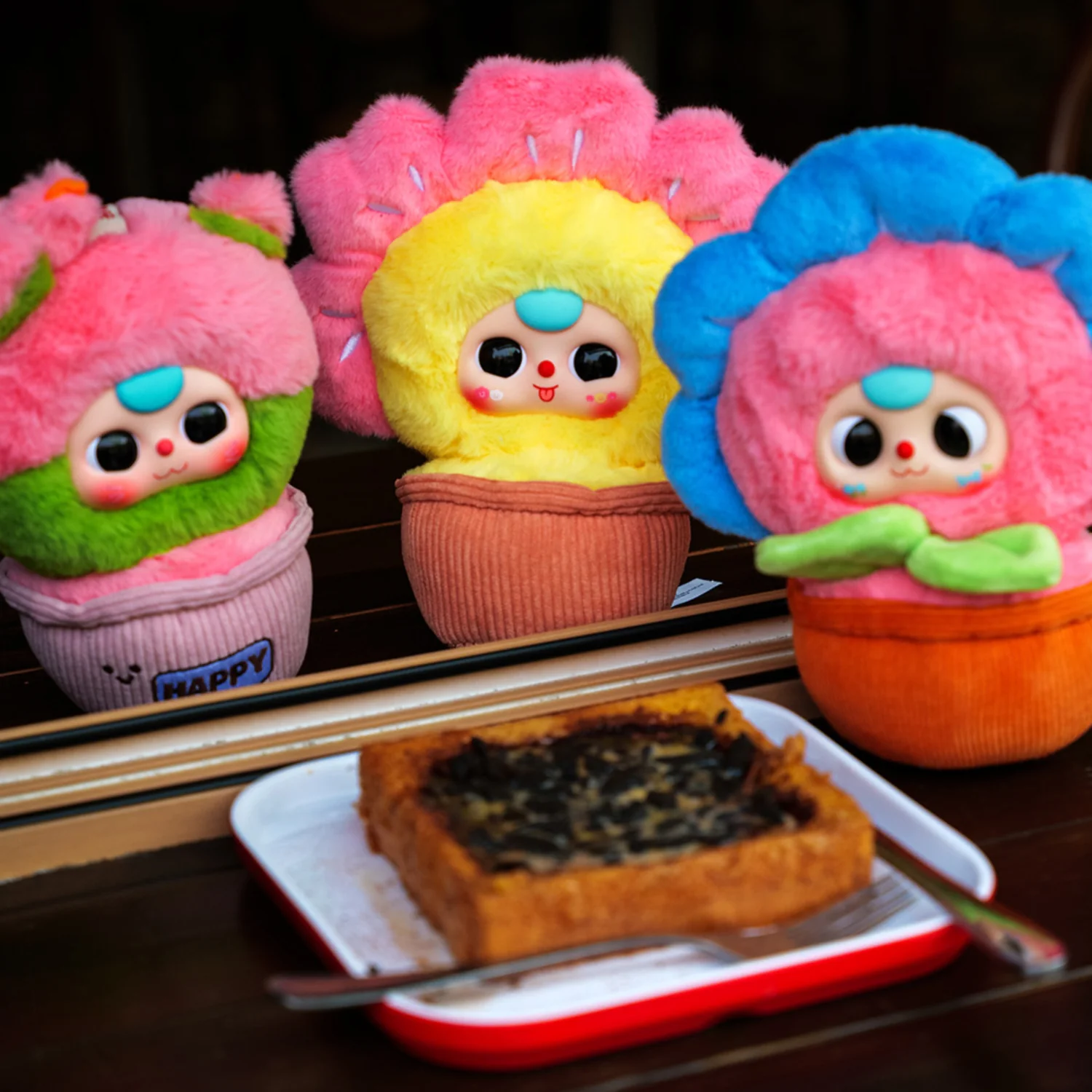 Three colorful plush toys with a plate of food on a table