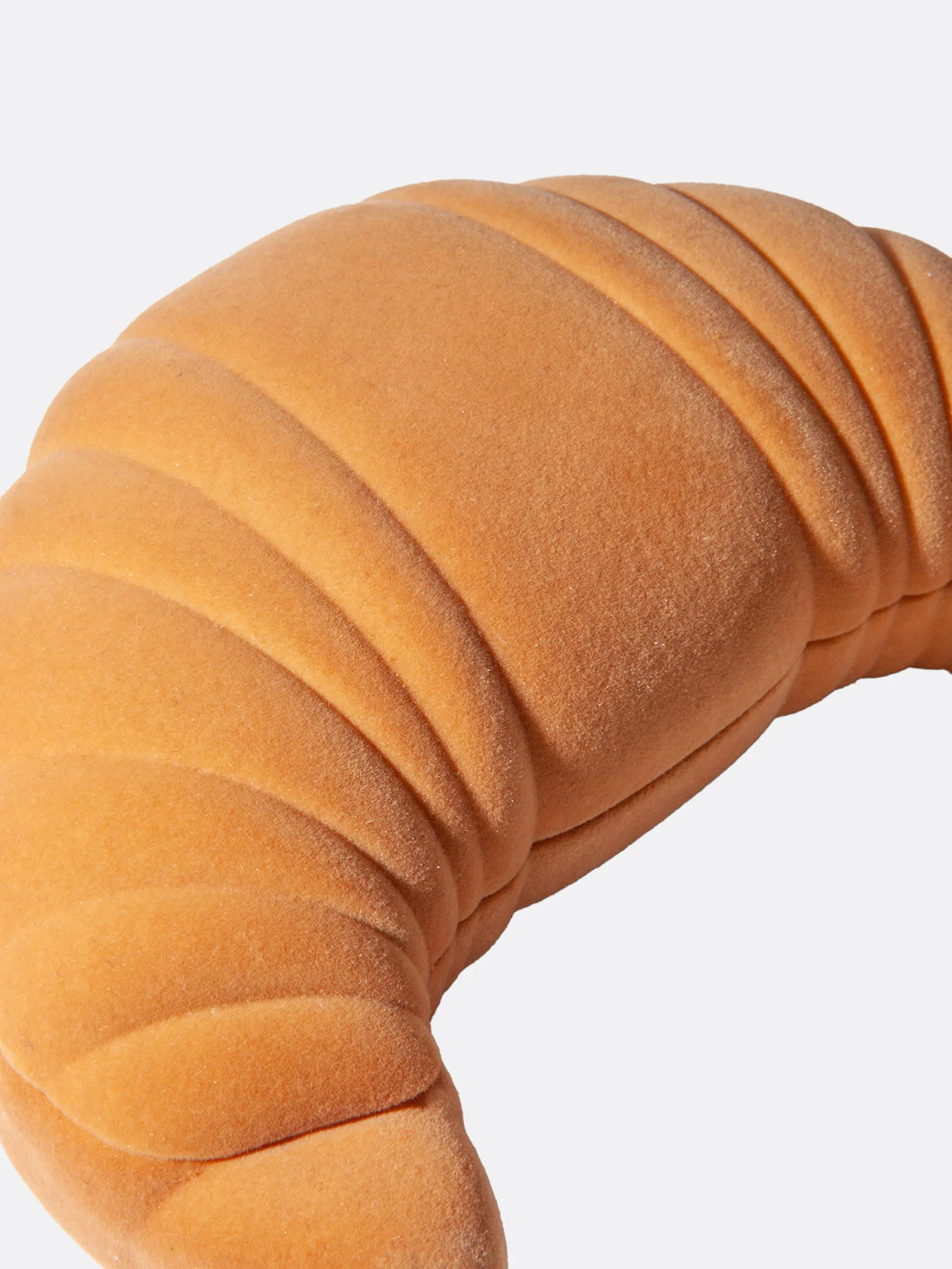 Orange crescent roll-shaped pillow on a white background