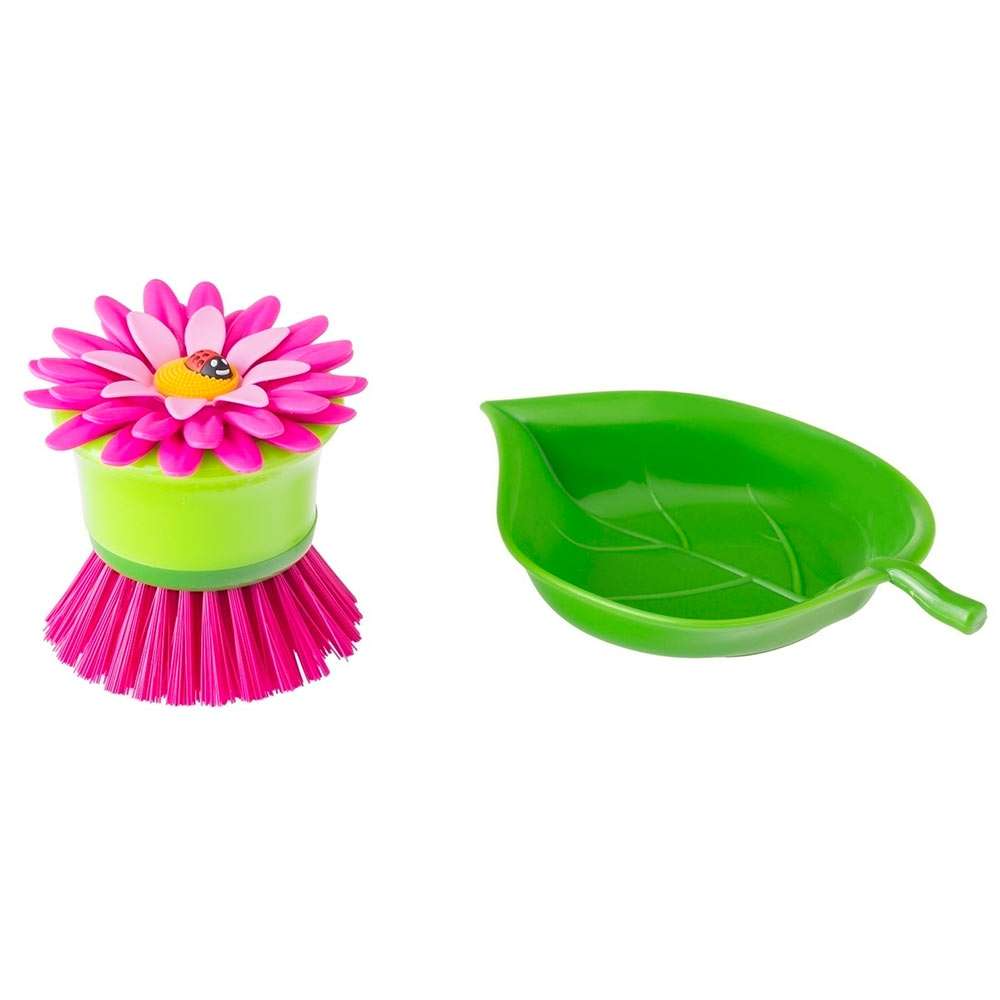 Cleaning brush with pink flower head and green handle, next to a green leaf-shaped container on a white background.