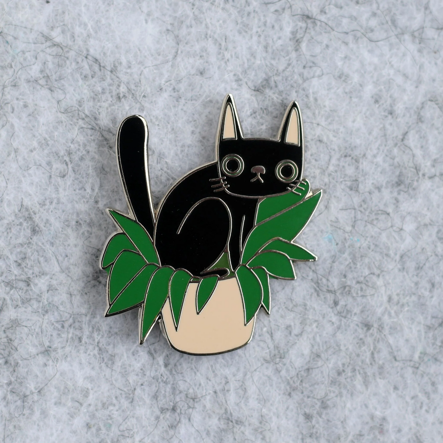 Black cat pin with green leaves on a gray background