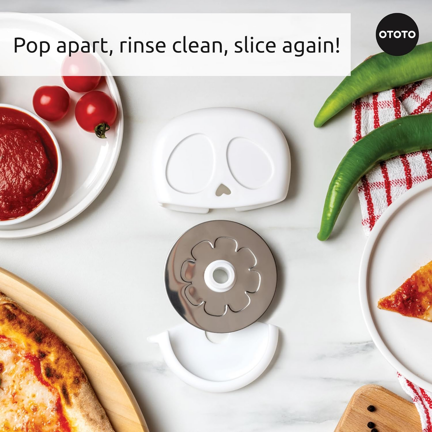 A disassembled pizza cutter on a marble bench surrounded by pizza ingredients.
