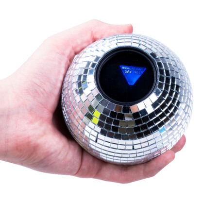 Hand holding a disco ball with a speaker inside on a white background