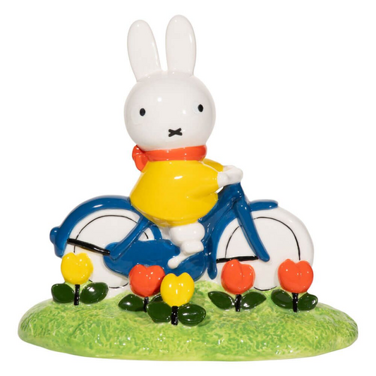 White  Miffy rabbit figure on a bicycle with flowers and grass on a white background