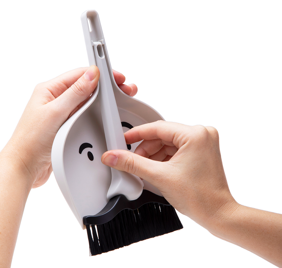 A pair of hands detaching the dustpan from the brush on a white background.