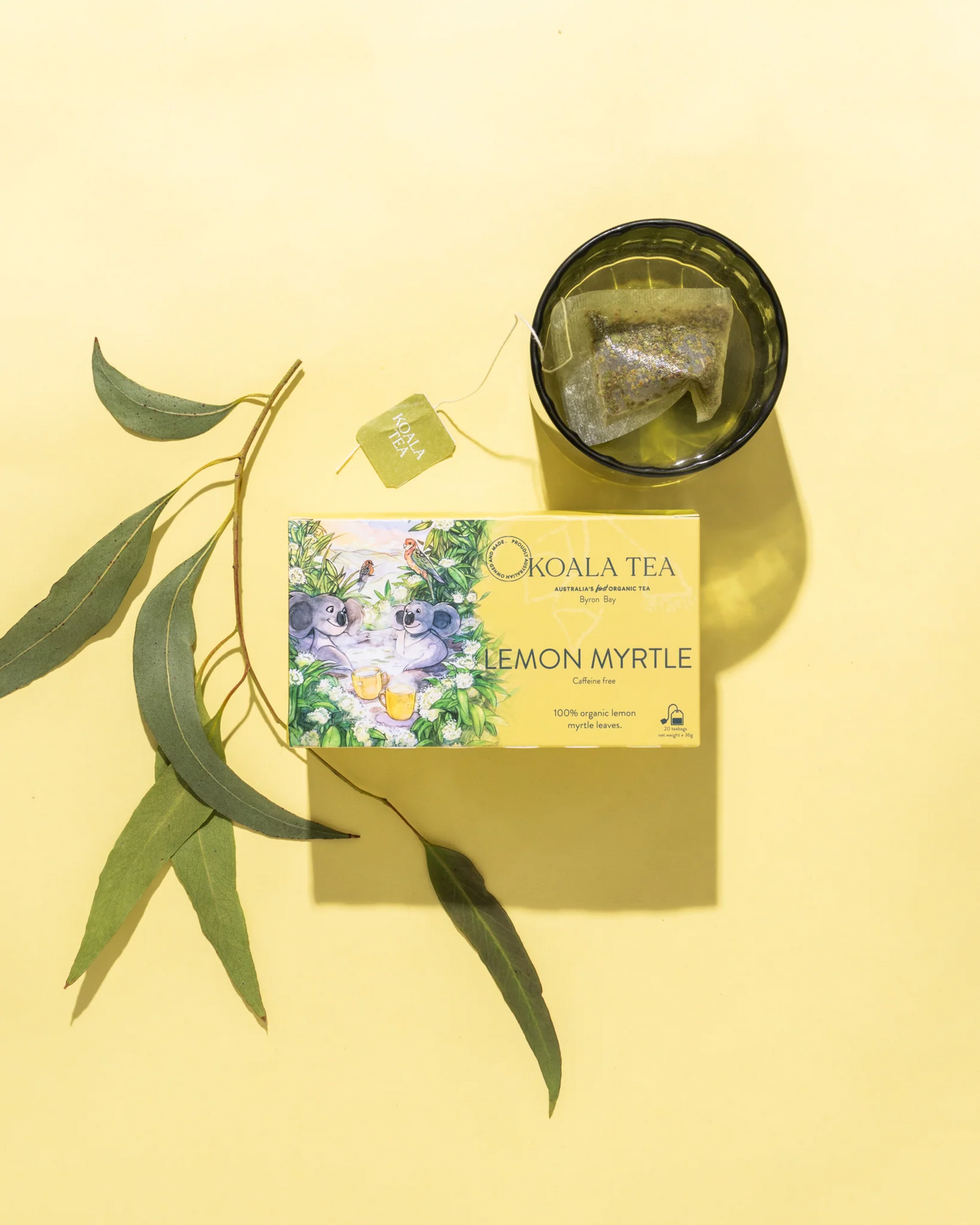 Koala Tea Lemon Myrtle packaging with tea bags in a glass on a yellow background