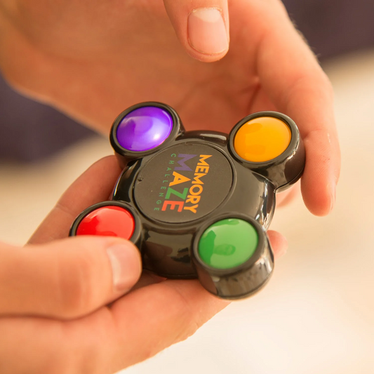 Hand holding a fidget spinner with colored buttons labeled 'Memory Maze'.