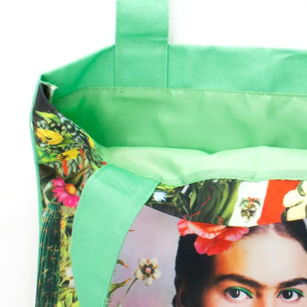 Green tote bag with a colorful design featuring a portrait and floral elements.