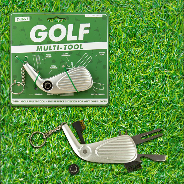 A 7-in-1 golf multi-tool keychain shown both in its green retail packaging and unfolded on a green grass-like surface. The silver metal tool includes a golf club head, fork, screwdriver, bottle opener, nail file, and small accessories.