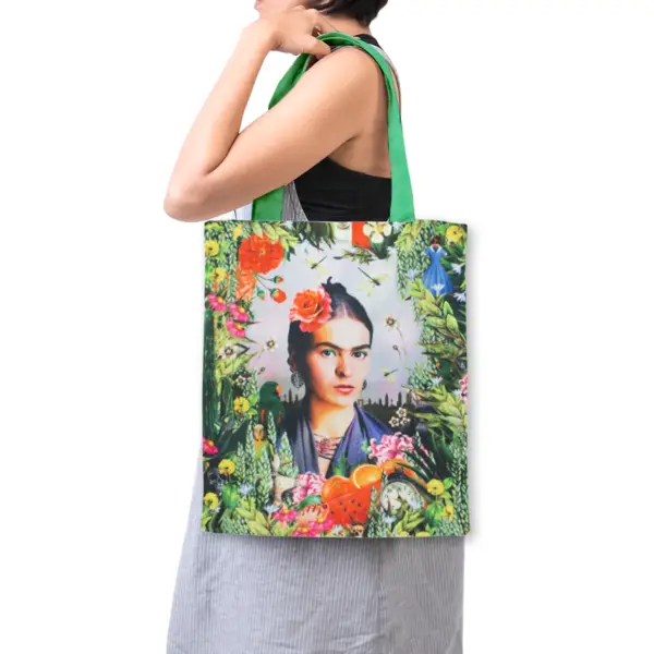 Tote bag with a design of a portrait and floral elements, held by a person.