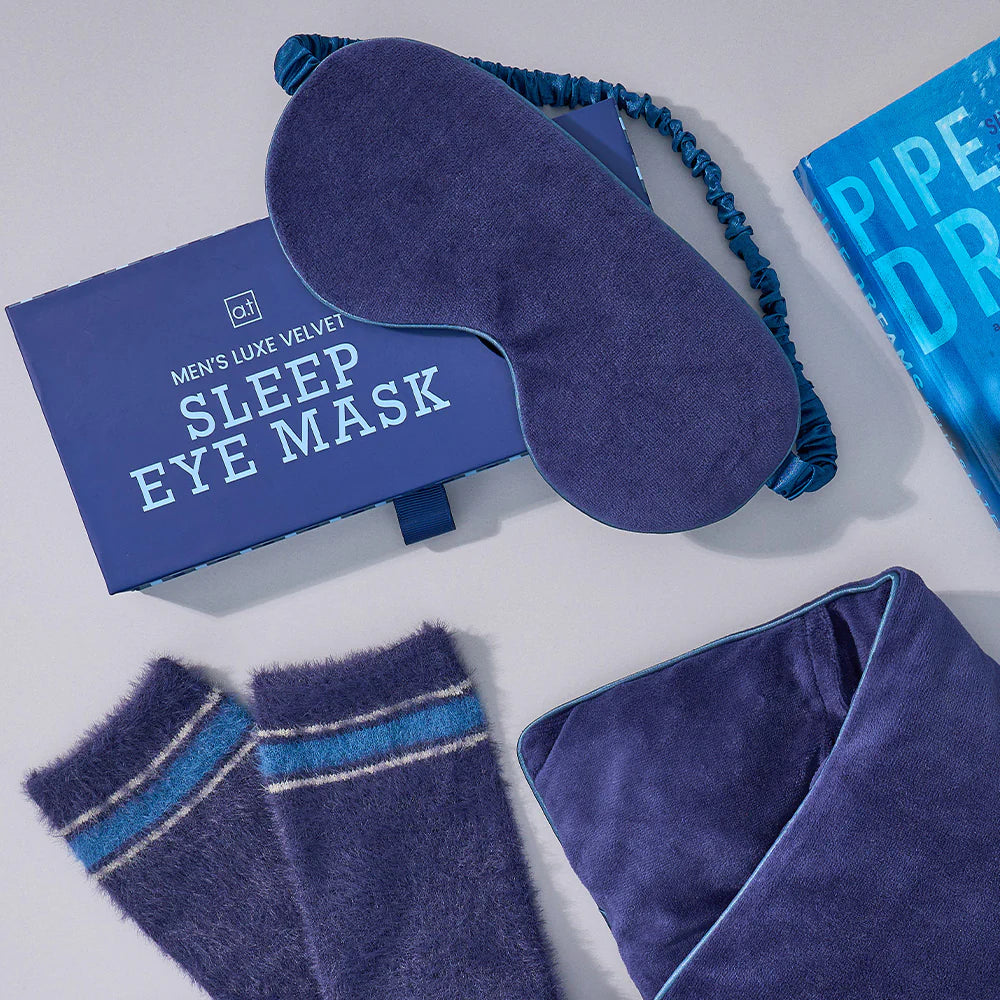 Blue sleep eye mask with matching socks and towel on a white background