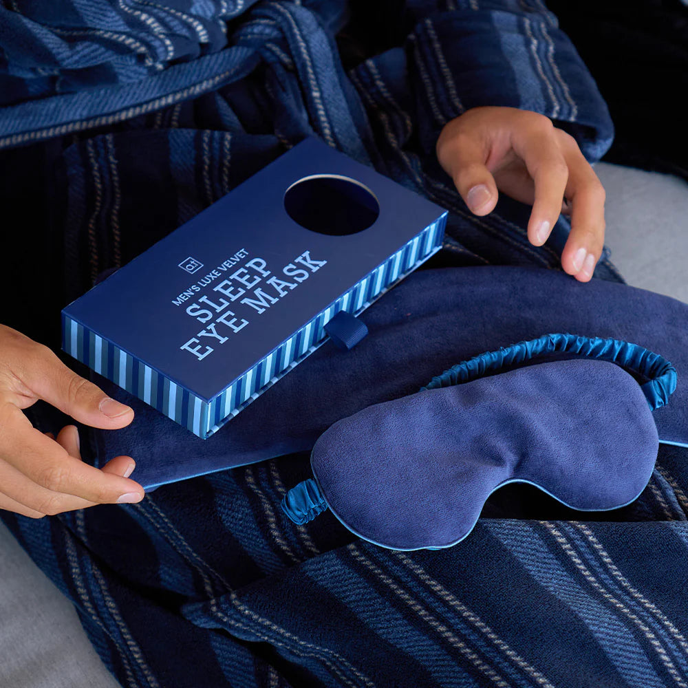 Blue sleep eye mask with packaging on a plaid fabric background