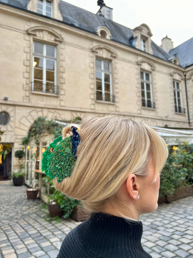 Person with styled hair in an outdoor setting with a building in the background