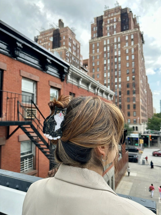 Person with a hair cat accessory in an urban setting with tall buildings.