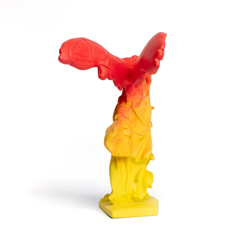Back view of a red and yellow winged statue of victory in flight